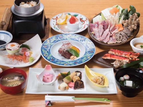 a wooden table with plates of food on it at Tokiwaso in Miyakonozyō