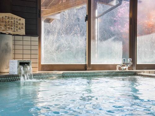 a large swimming pool in a room with a window at Tokiwaso in Miyakonozyō