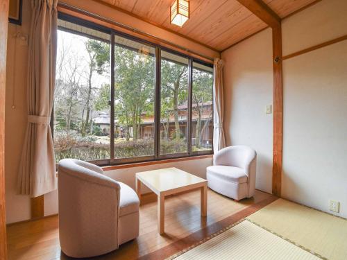 a living room with two chairs and a table and a window at Tokiwaso in Miyakonozyō