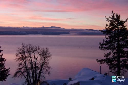 a view of a lake at sunset with trees at Pepper Tree Inn Tahoe City in Tahoe City