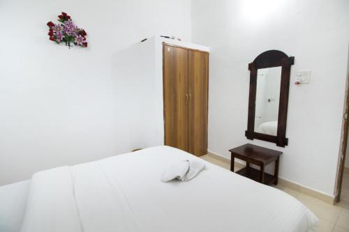 a bedroom with a white bed and a mirror at Brittos Homestay in Mandrem