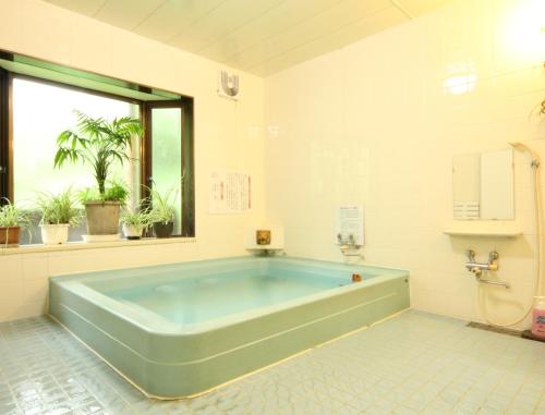 een grote badkamer met een groot blauw bad bij Yokokura Ryokan in Nagano