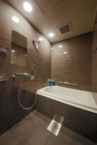 a bathroom with a bath tub and a shower at Hotel Code Shinsaibashi in Osaka