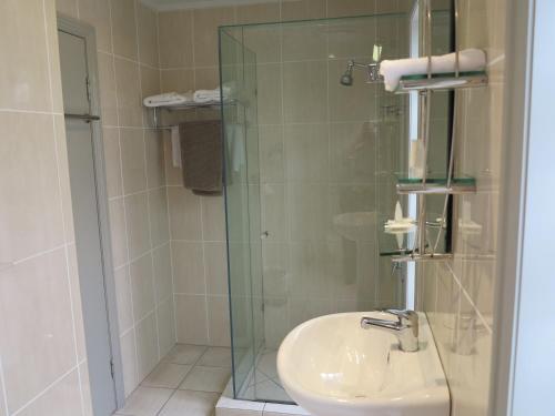 a bathroom with a sink and a glass shower at Shangri-La Gardens in Brisbane