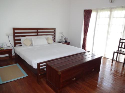 ein Schlafzimmer mit einem großen Bett und Holzboden in der Unterkunft Irinjalakuda House in Udagamandalam