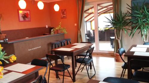 un restaurante con paredes de color naranja, mesas y sillas en Willa Nova en Karwia
