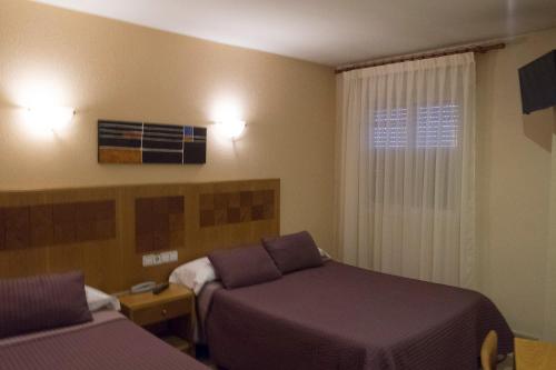 Hostal Azul في ألمولار: غرفة فندقية بسريرين ونافذة