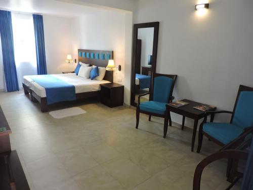 a bedroom with a bed and two blue chairs at Pigeon Island Beach Resort and Spa in Nilaveli