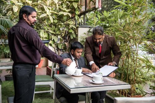 a group of men standing around a table with a laptop at Hotel Oriental Aster - Mumbai International Airport in Mumbai
