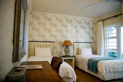 una camera da letto con due letti, un tavolo e una finestra di Princes Lodge Guesthouse a East London