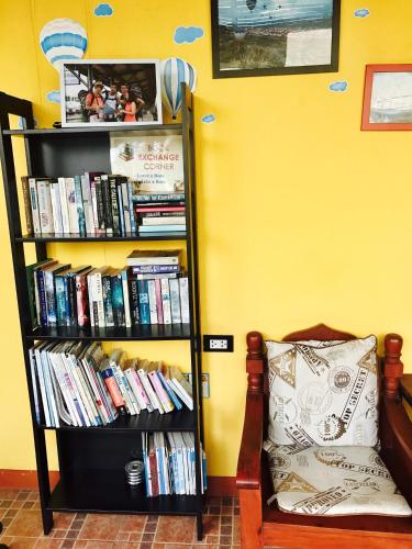 a book shelf filled with books next to a chair at At Home Hostel, Pak Chong in Pak Chong