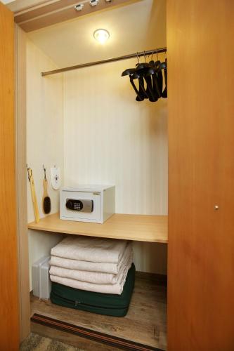 a closet with a microwave and towels on a shelf at Savoy Hotel Myeongdong in Seoul