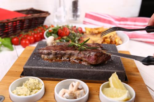 a steak on a cutting board with bowls of food at Agroturystyka Klekusiowo in Bolesławiec