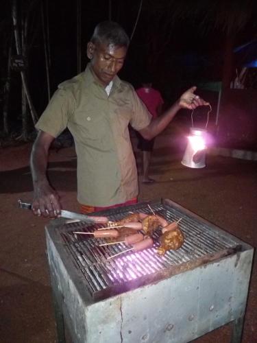 a man is cooking food on a grill at Hidden Jungle Village in Wilpattu