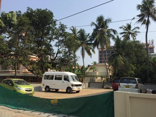 a white van parked in a parking lot with palm trees at Mega Tourist Home Palarivattom in Cochin