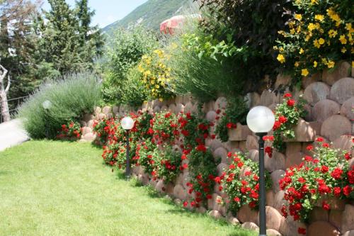 a garden with red flowers on a stone fence at Hotel Oasi Beach in Malcesine