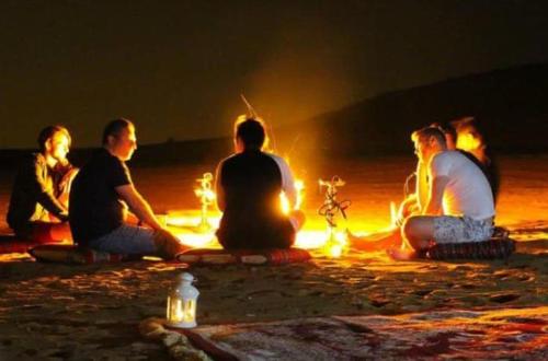 a group of people sitting around a fire at night at Mariyan Desert Safari Camp in Sām