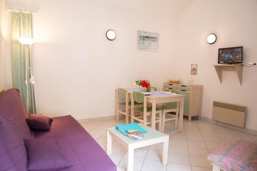 a living room with a purple couch and a table at Village de gîtes de Blajoux in Quézac