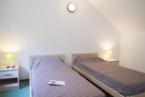 two beds in a room with a clock on the wall at Village de gîtes de Blajoux in Quézac