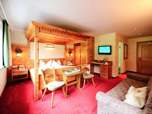 a bedroom with a bed and a desk and a couch at Alpenhof Pitztal in Sankt Leonhard im Pitztal