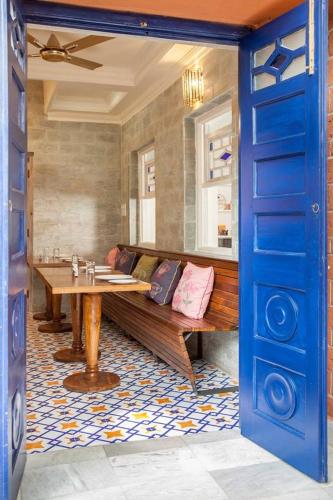 a room with a bench and a table and a blue door at The Ivy House in Kolkata