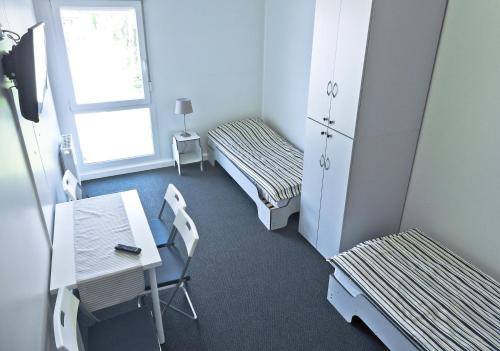 una habitación con dos camas y una mesa y sillas en Hostel Września, en Września