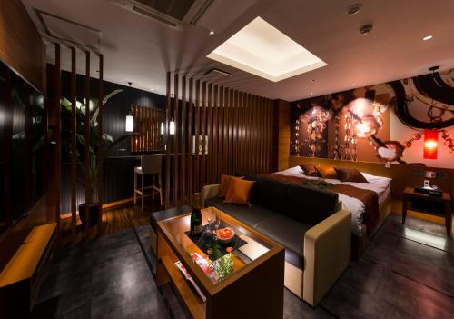 a living room with a couch and a bed at Hotel Plant Garden Resort (Adult Only) in Toyokawa
