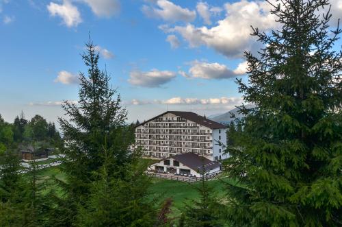 un grande edificio in mezzo ad alcuni alberi di Cheile Gradistei Fundata Resort a Fundata