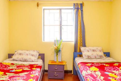 two beds in a room with a window and a table at Colours Club and Spa in Kigali