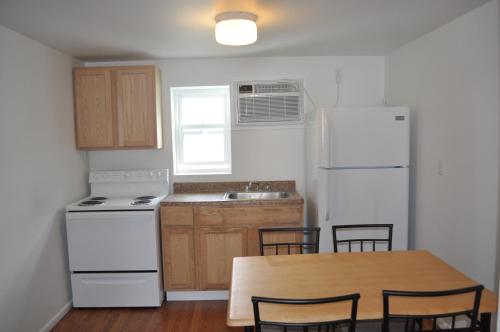 cocina con mesa de madera y nevera blanca en South Wind Apartments, en Ocean City