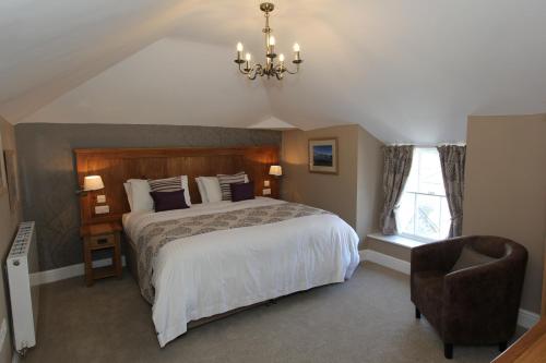 a bedroom with a bed and a chair and a chandelier at Plas Yn Dre in Bala