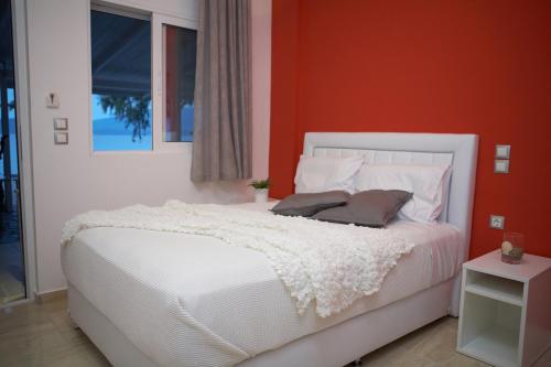 1 dormitorio con cama blanca y pared roja en Ammos Beach en Glífa