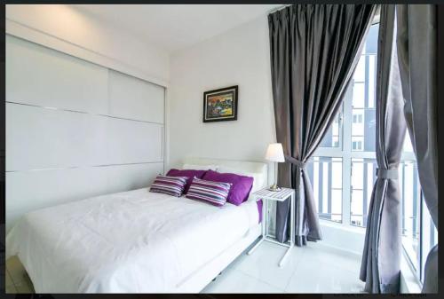 a bedroom with a bed with purple pillows and a window at Relax & Chill at Malacca River in Melaka