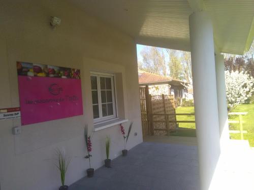 a front porch of a house with a pink sign on the wall at Chambre d'Hôtes Les Macarons de Tata in Sainte-Eulalie