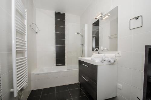 a white bathroom with a sink and a bath tub at Appartement Lavande in Chamonix