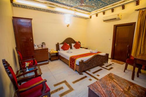 a bedroom with a bed and chairs in a room at Nahargarh Haveli-Near Train station Metro in Jaipur