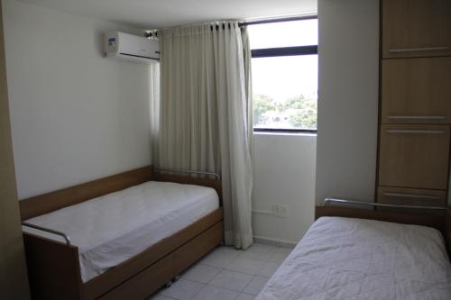 a small bedroom with two beds and a window at Portugal Flat in João Pessoa