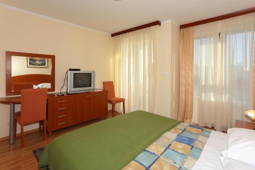 1 dormitorio con cama y vestidor con TV en Apartments and Rooms Astoria, en Trogir