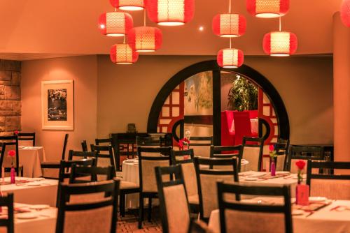 a dining room with tables and chairs and chandeliers at Avani Lesotho Hotel & Casino in Maseru