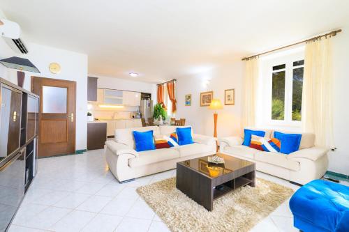 a living room with two couches and a tv at Holiday Home Obrov in Kaštela