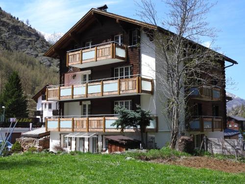 een groot gebouw met een boom ervoor bij Haus Alpenperle in Saas-Almagell