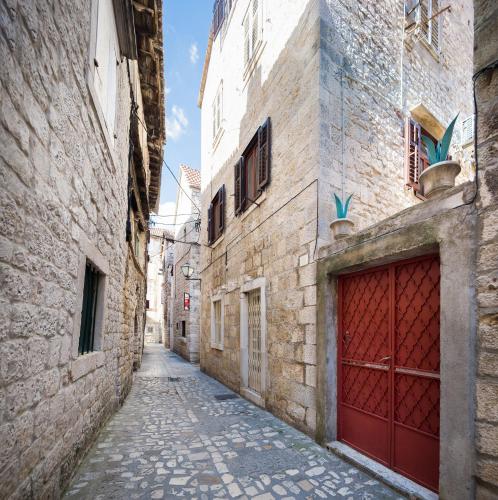 an alley in an old town with a red garage at Apartment Patricia in Trogir