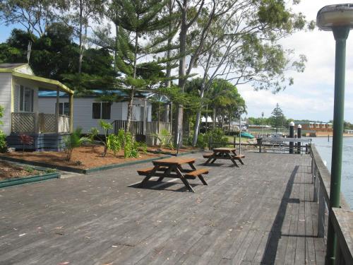 dos mesas de picnic en un paseo junto al agua en Edgewater Holiday Park, en Port Macquarie