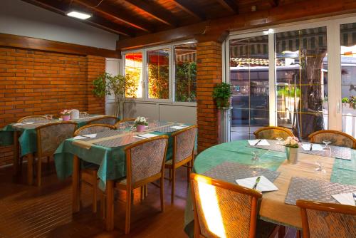 uma sala de jantar com mesas, cadeiras e janelas em Hotel Rinaldo Apartment em Borgomanero