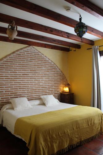 sypialnia z dużym łóżkiem z ceglaną ścianą w obiekcie La Posada de Manolo w mieście Toledo