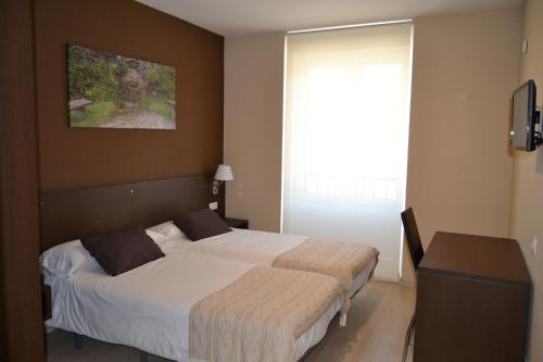 um quarto com uma cama grande e uma janela em Pension-Albergue Lemos em Triacastela