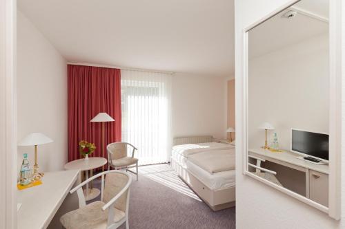 ein Hotelzimmer mit einem Bett und einem Spiegel in der Unterkunft Hotel Reutereiche in Reuterstadt Stavenhagen