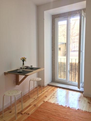 a room with a table and two stools in front of a window at Casa Amarela in Aveiro