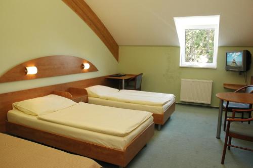 a room with three beds and a table and a television at Hotel Břízky in Jablonec nad Nisou