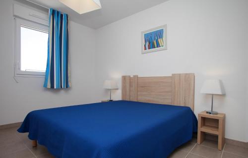 a bedroom with a blue bed and a window at Résidence Odalys Les Iles du Morbihan in Baden